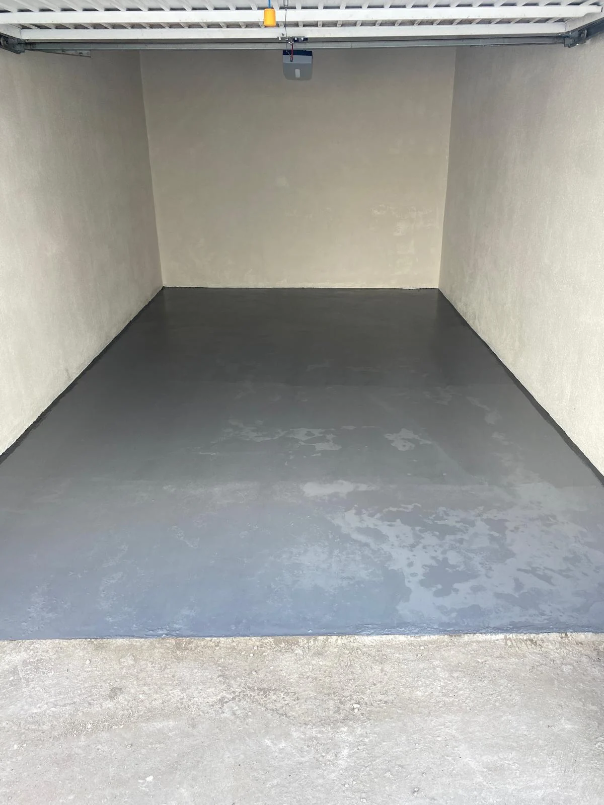 Garage après rénovation : murs blancs et sol fini